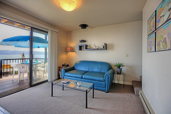 A leather sofa in the living room of The Beach House at Tyee folds out into a comfortable double bed. The sliding glass doors lead out onto the deck.