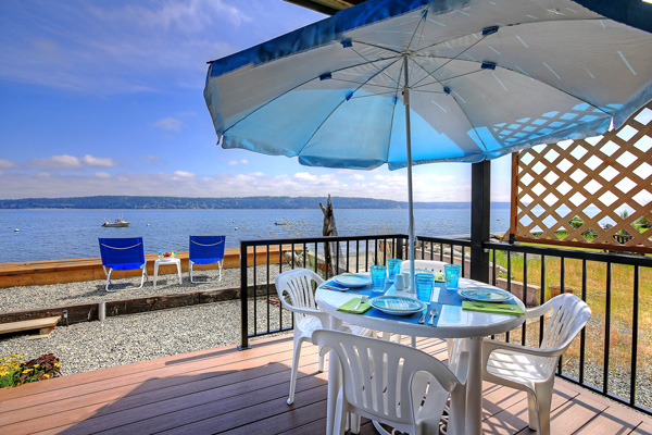 A dining table with umbrella is located just outside the sliding glass doors leading to the deck at The Beach House at Tyee.